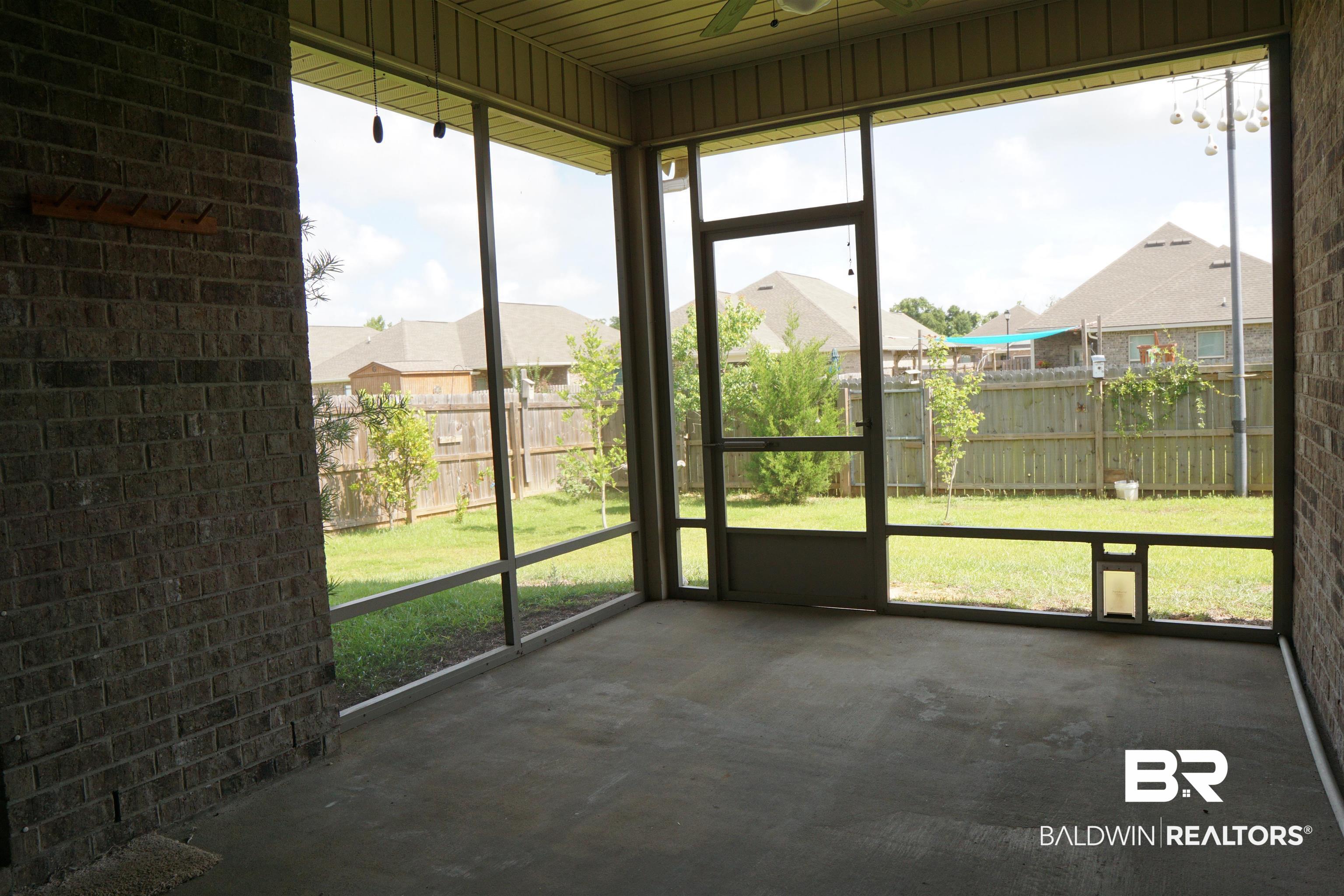 1060 Chloe Street Foley, AL 36535 - Photo 23 of 28 Spacious screened patio featuring a concrete floor, brick wall, and access to a fenced backyard