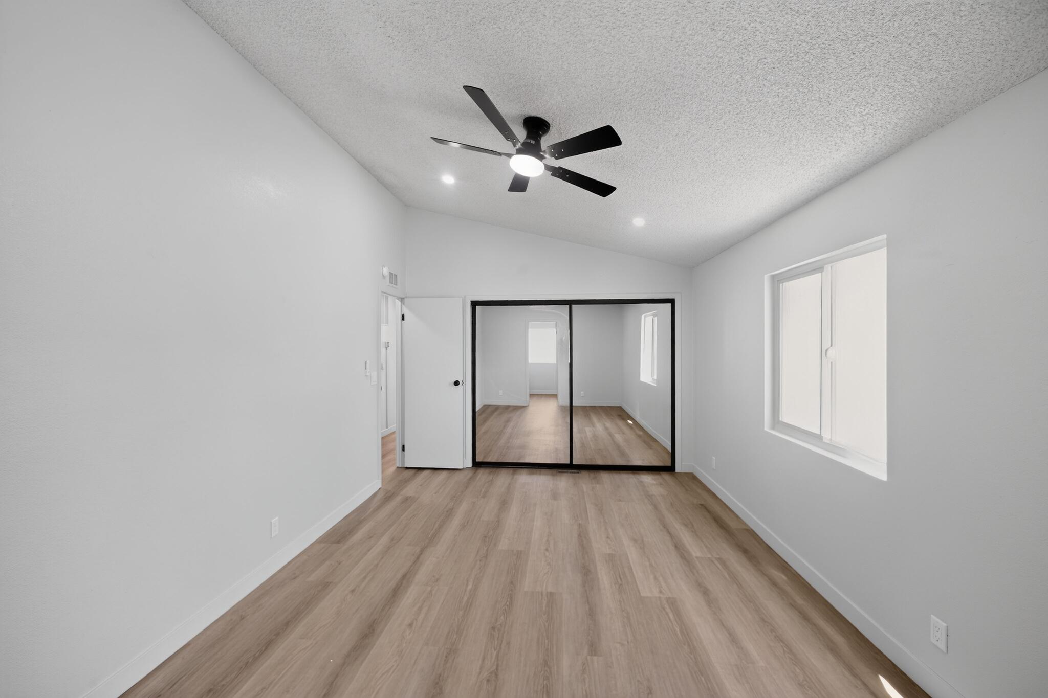 15181 Van Buren Boulevard, Unit 102 Riverside, CA 92504 - Photo 21 of 29 an empty room with wooden floor a ceiling fan and windows