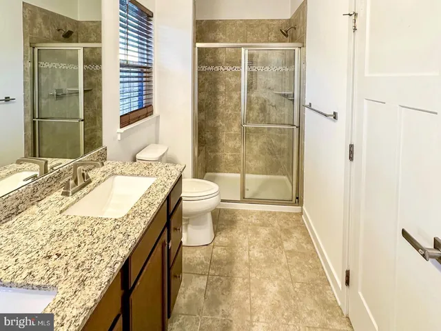 a bathroom with a granite countertop sink a toilet and shower