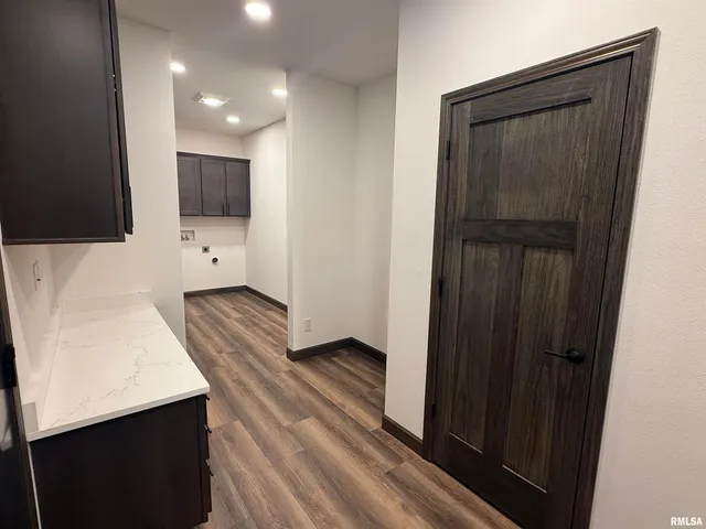 a view of hallway with stainless steel appliances wooden floor and staircase