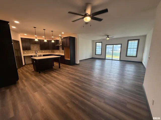 a dining hall with stainless steel appliances kitchen island a stove a refrigerator cabinets and living room view