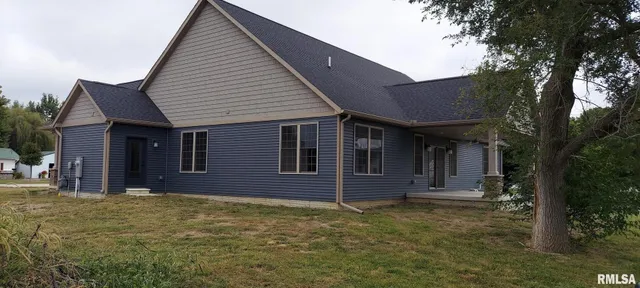 a view of a house with a small yard and a large tree