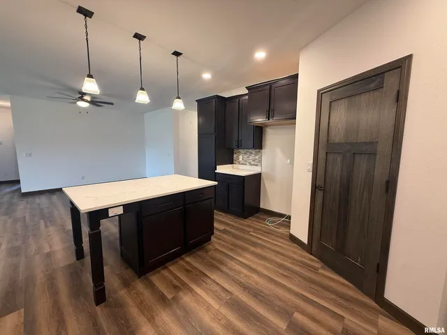 a kitchen with stainless steel appliances granite countertop a refrigerator a sink and a wooden floor