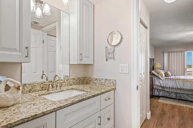 a en suite bathroom with a granite countertop sink and a mirror