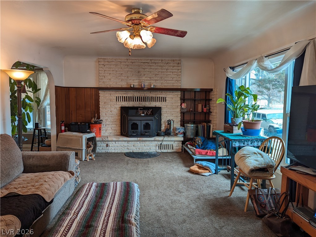 561 Main Street Caliente, NV 89008 - Photo 8 of 32 Living area featuring ceiling fan, carpet flooring, and a wood stove