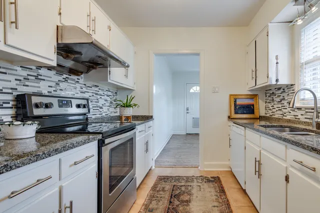 a kitchen with stainless steel appliances granite countertop a stove a sink and a microwave