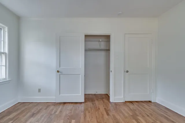 a view of an empty room with wooden floor and closet