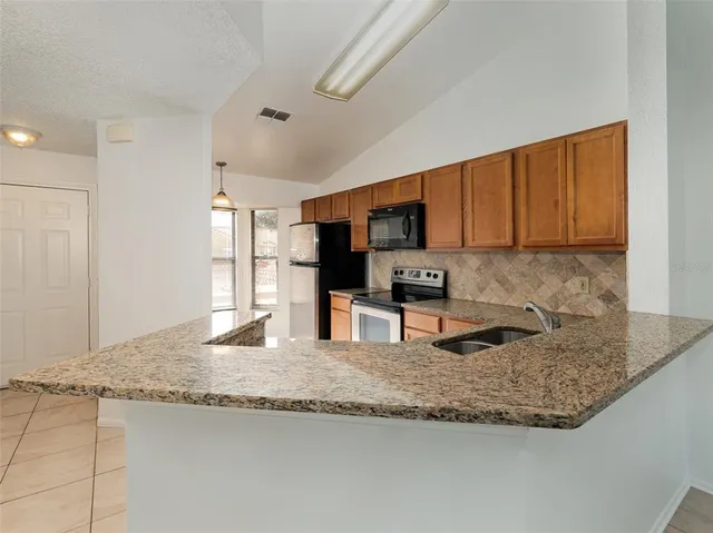 a kitchen with granite countertop a sink a counter top space cabinets and stainless steel appliances