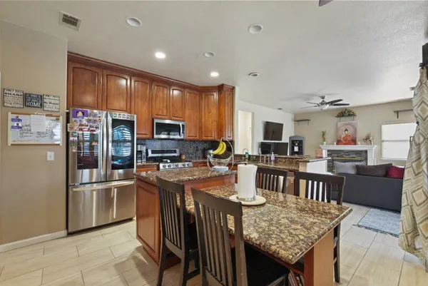 a kitchen with stainless steel appliances granite countertop a refrigerator a stove top oven a sink a dining table and chairs