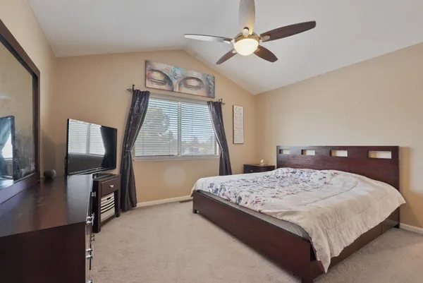 a bedroom with a bed next to a window with a flat screen tv