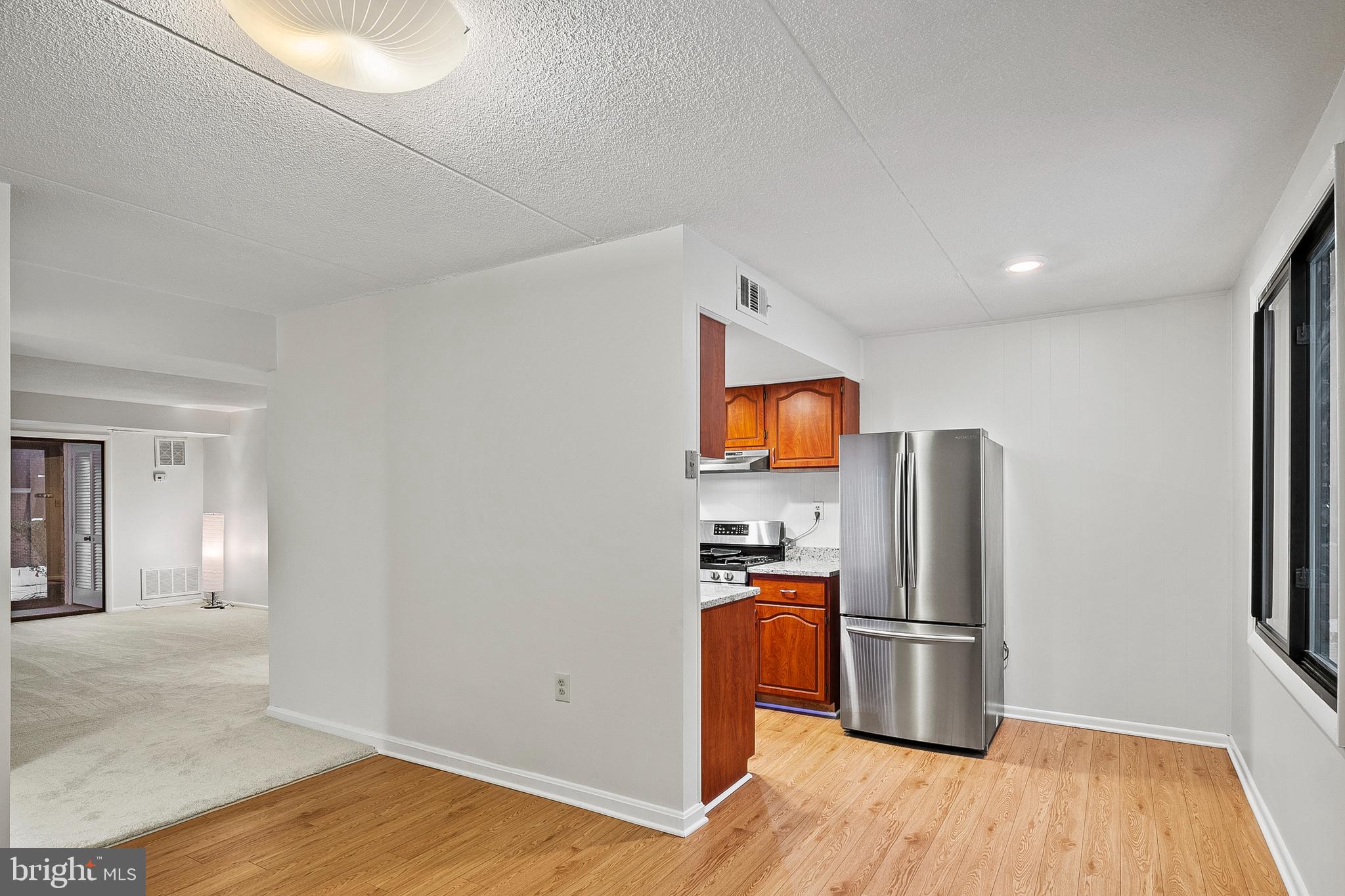 5232 West Running Brook Road, Unit 101 Columbia, MD 21044 - Photo 9 of 39 a view of a refrigerator in kitchen and a room with wooden floor