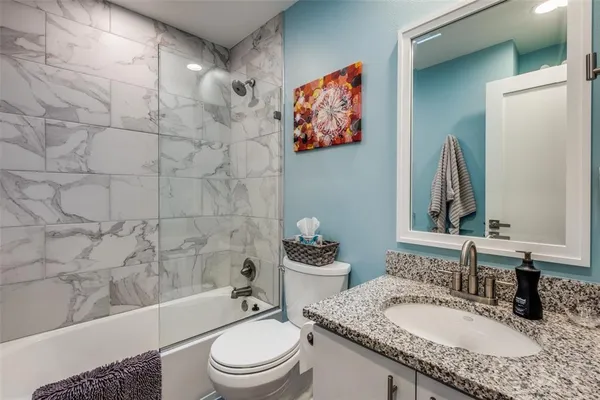 a bathroom with a granite countertop toilet a sink and a bathtub