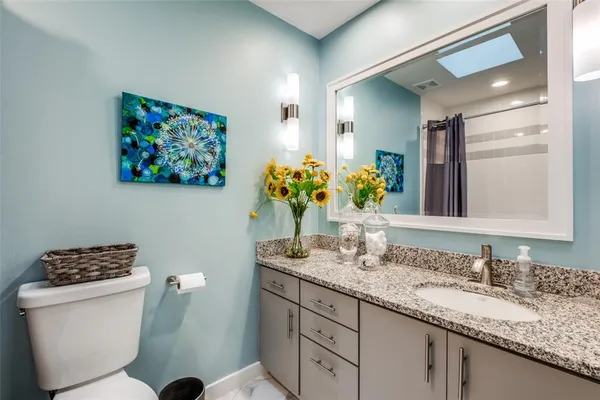 a bathroom with a granite countertop toilet sink and mirror