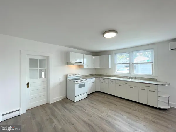 a large white kitchen with granite countertop a stove top oven a sink and dishwasher with wooden floor