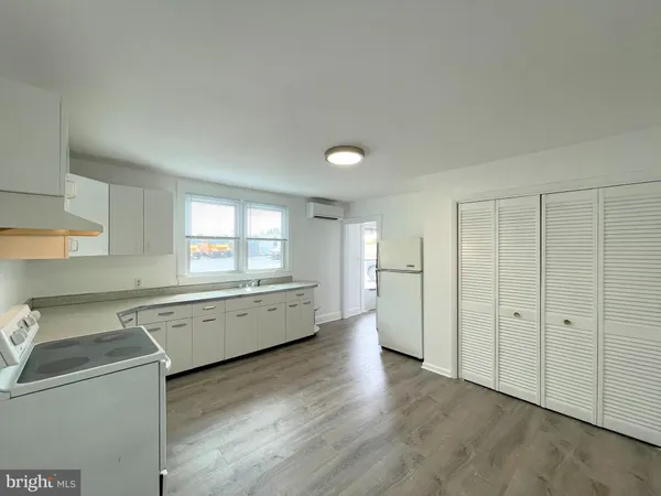a large white kitchen with a sink a window and stainless steel appliances