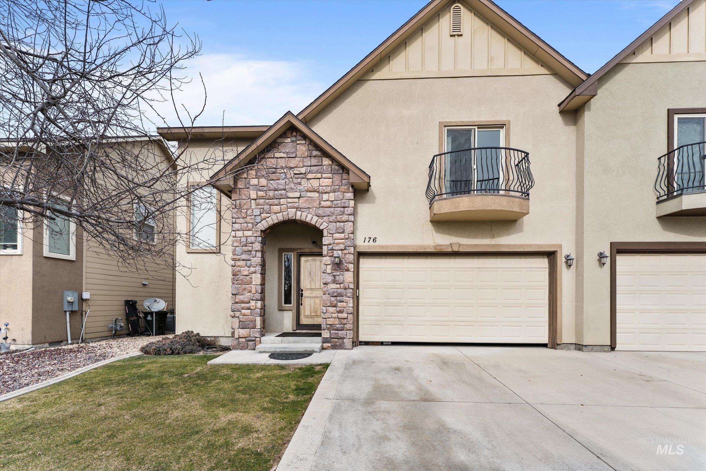 View of front of house featuring stucco siding, concrete driveway, a balcony, stone siding, and a garage
