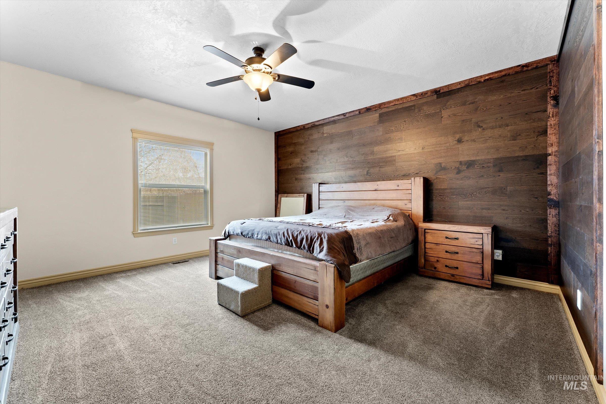 176 East Breinholt Street Meridian, ID 83646 - Photo 13 of 39 Bedroom with wooden walls, light carpet, ceiling fan, and an accent wall