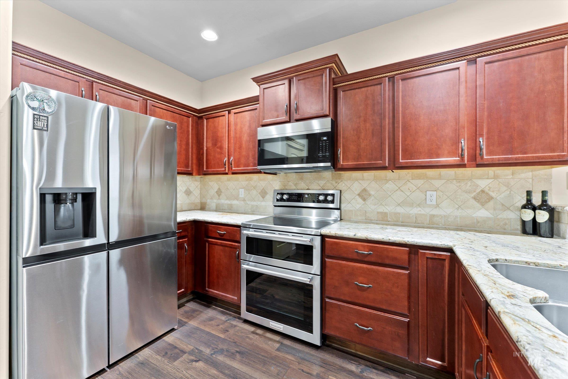 176 East Breinholt Street Meridian, ID 83646 - Photo 6 of 39 Kitchen with stainless steel appliances, light stone counters, dark brown cabinets, dark wood finished floors, and recessed lighting