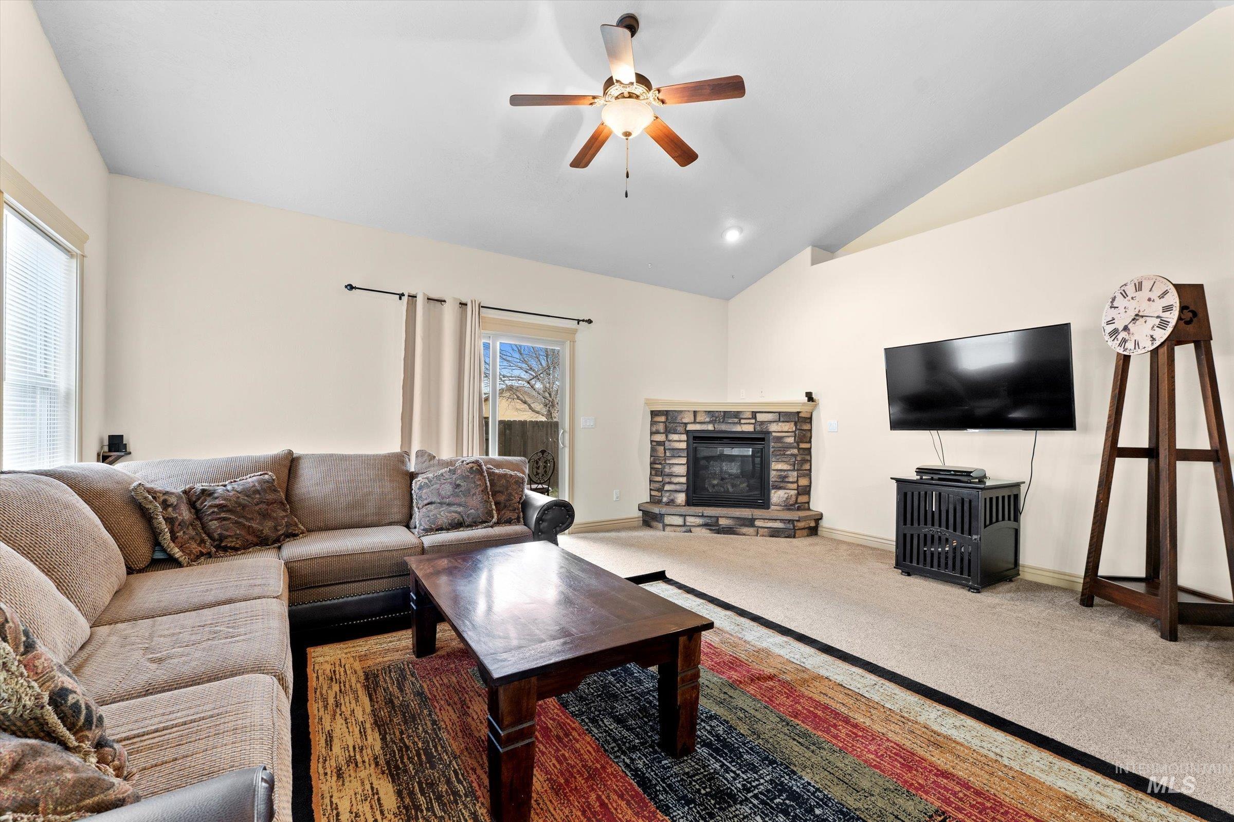176 East Breinholt Street Meridian, ID 83646 - Photo 10 of 39 Living area featuring a stone fireplace, carpet floors, a ceiling fan, and vaulted ceiling