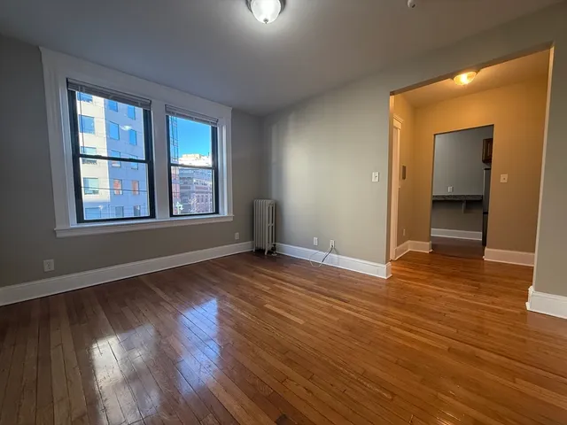 a view of an empty room with wooden floor and a window