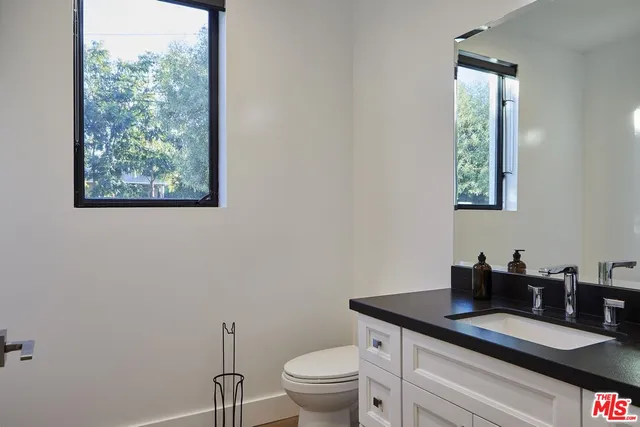 a bathroom with a granite countertop toilet a sink and a mirror