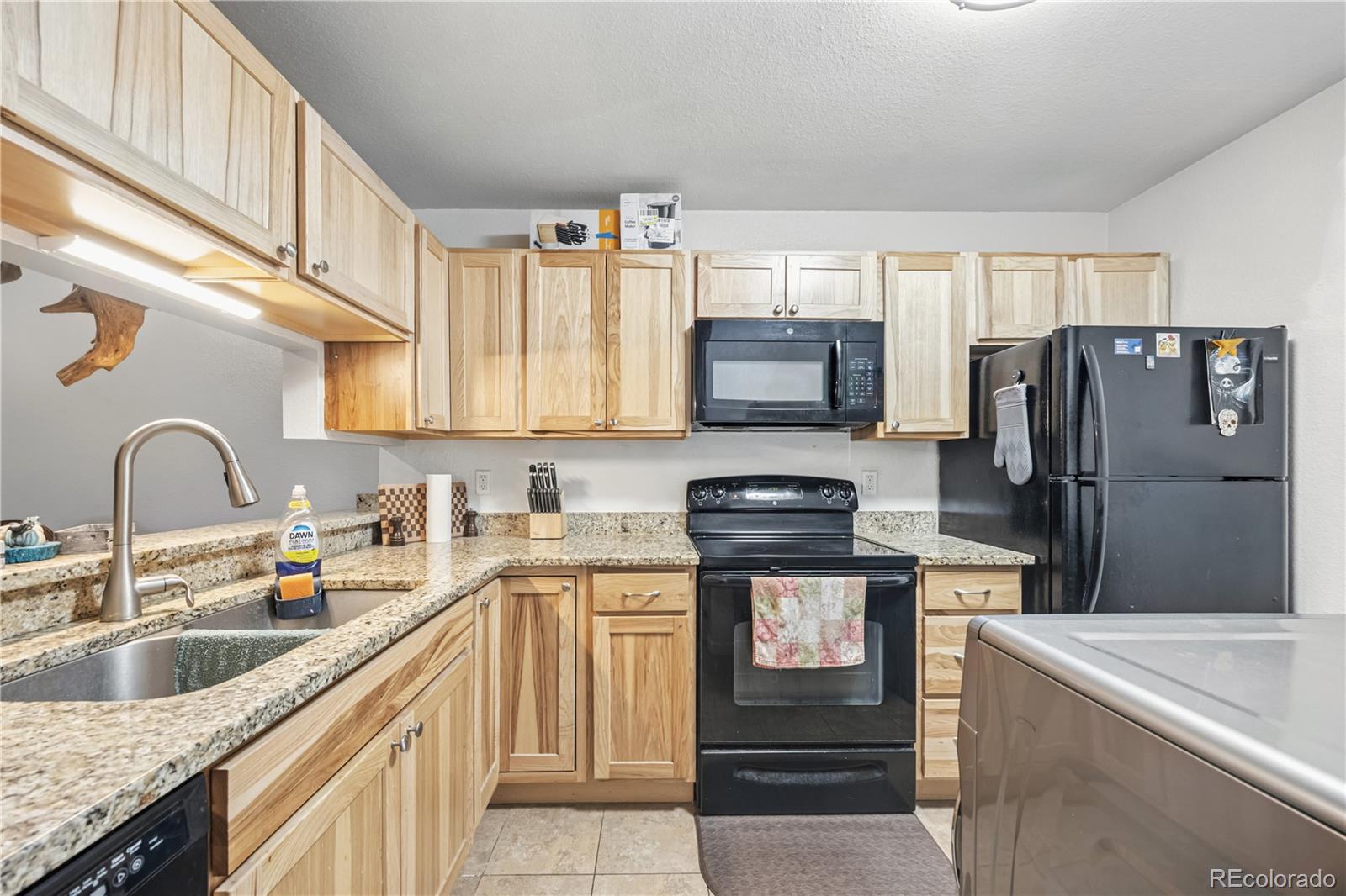 7740 West 35th Avenue, Unit 214 Wheat Ridge, CO 80033 - Photo 6 of 20 a kitchen with stainless steel appliances granite countertop a refrigerator a stove and a sink