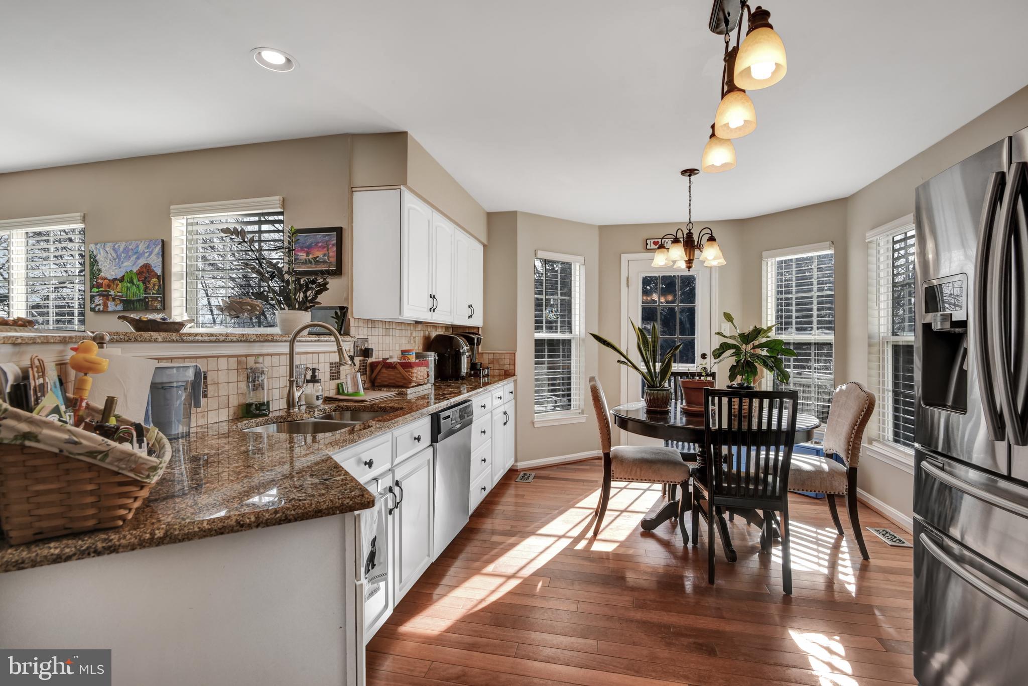 5944 Sandy Ridge Elkridge, MD 21075 - Photo 12 of 42 a kitchen with stainless steel appliances granite countertop a stove top oven a sink a dining table and chairs with wooden floor