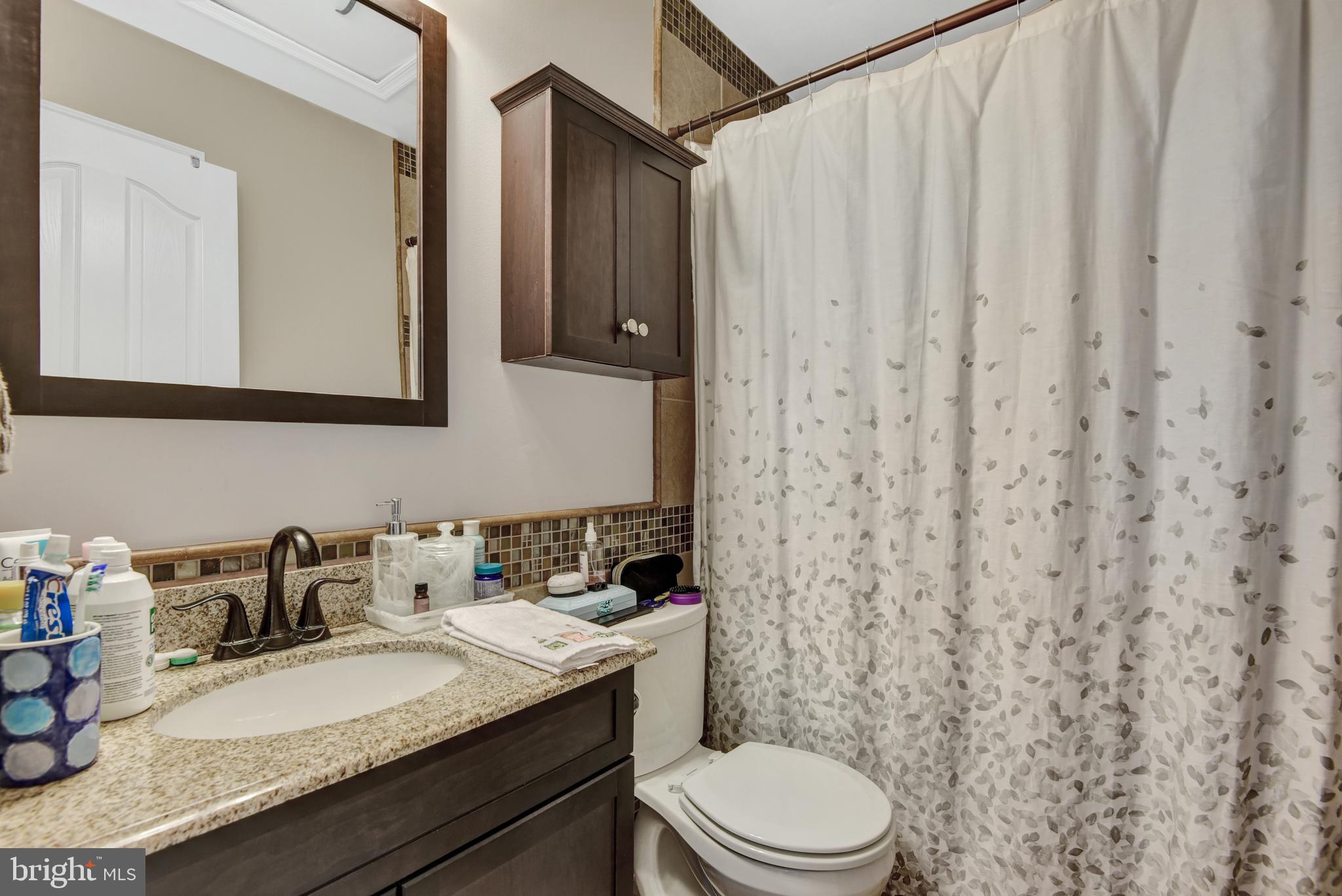 5944 Sandy Ridge Elkridge, MD 21075 - Photo 29 of 42 a bathroom with a granite countertop sink mirror vanity and toilet