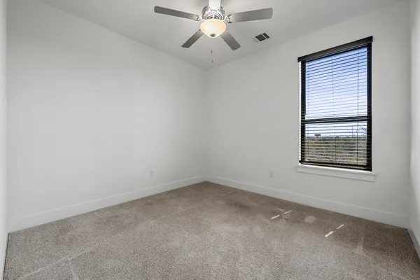 an empty room with a window and a fan