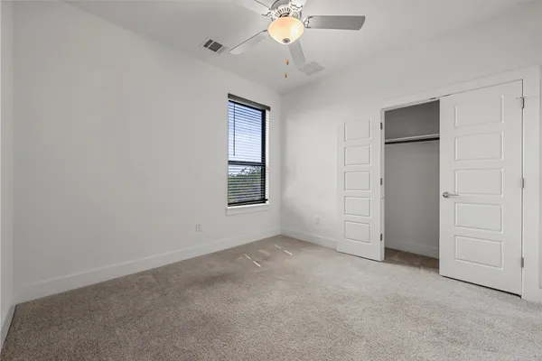 an empty room with chandelier fan and closet area