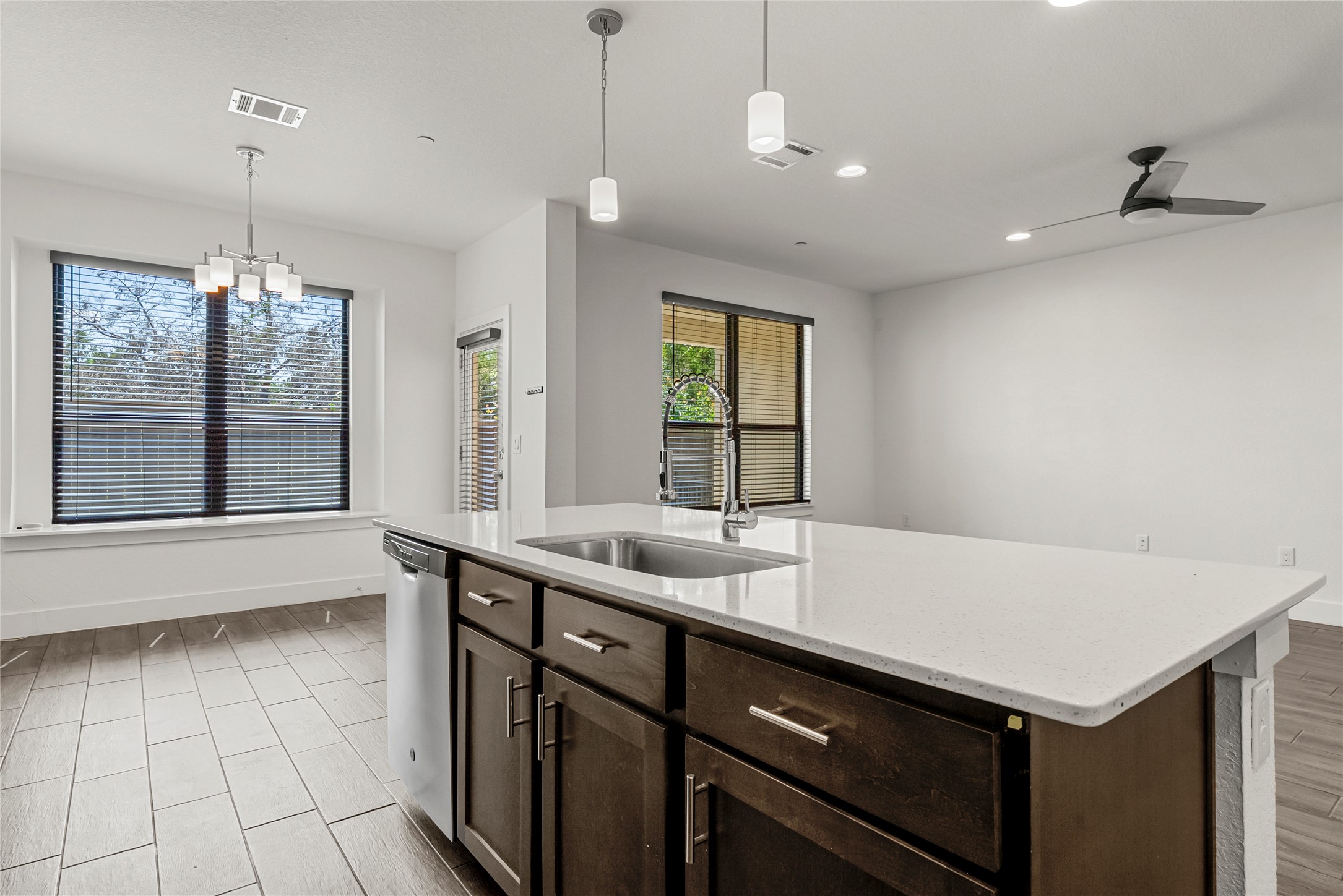 12315 Maypole Bend, Unit 1002 Austin, TX 78717 - Photo 6 of 29 Kitchen with dark wood finish cabinets, light stone countertops, ceiling fan, wood tiled floors, and stainless steel dishwasher