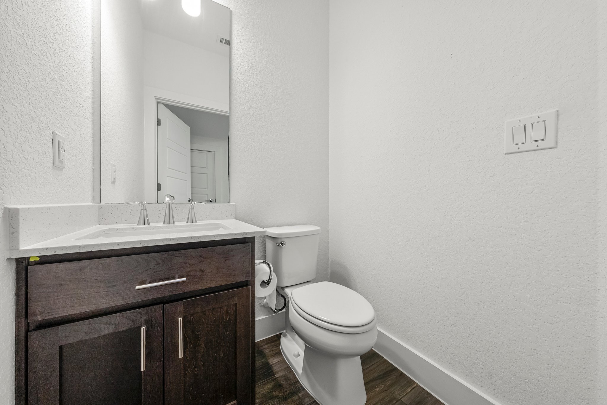 12315 Maypole Bend, Unit 1002 Austin, TX 78717 - Photo 7 of 29 Half bathroom with a textured wall, vanity, and dark wood-type flooring