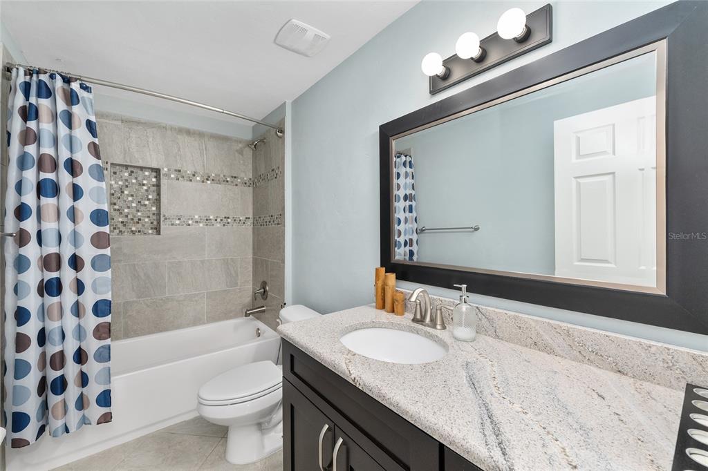 8942 Southwest 25 Road Gainesville, FL 32608 - Photo 17 of 22 a bathroom with a granite countertop sink toilet mirror and shower