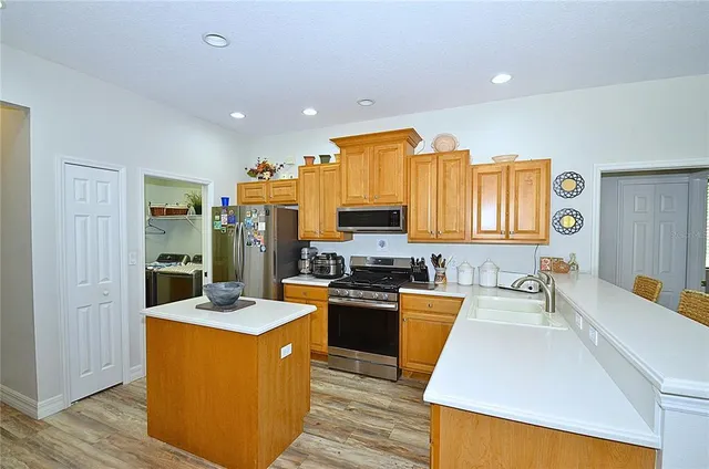 a large kitchen with stainless steel appliances kitchen island granite countertop a sink a stove and refrigerator
