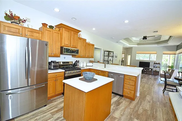 a kitchen with stainless steel appliances granite countertop a refrigerator a stove a sink a dining table and chairs with wooden floor