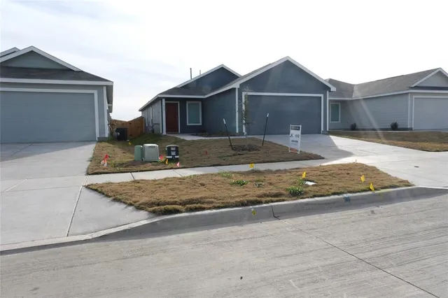 a view of a house with a small yard and large parking space
