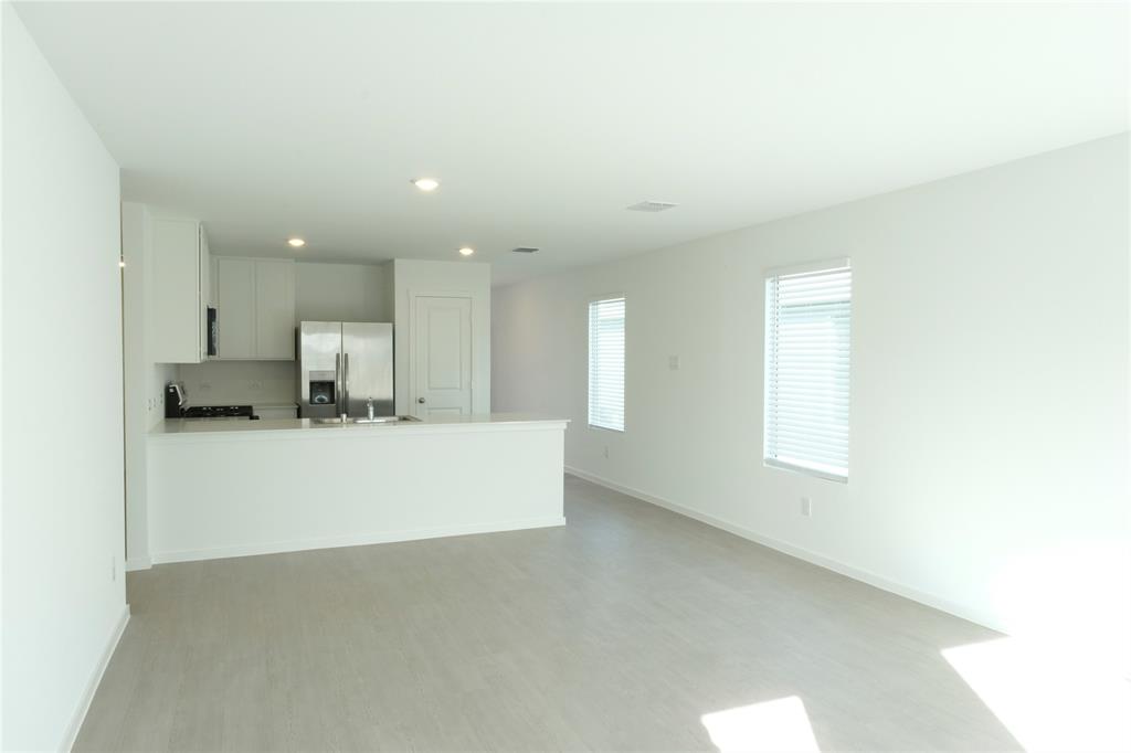 932 Calley Pear Trail Princeton, TX 75407 - Photo 6 of 16 a view of kitchen with kitchen island a sink wooden floor and a refrigerator