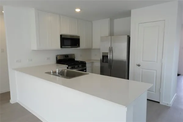 a kitchen with stainless steel appliances a refrigerator a sink a stove a microwave and wooden cabinets