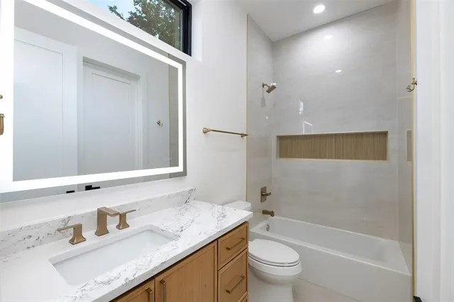a bathroom with a granite countertop sink a toilet and shower