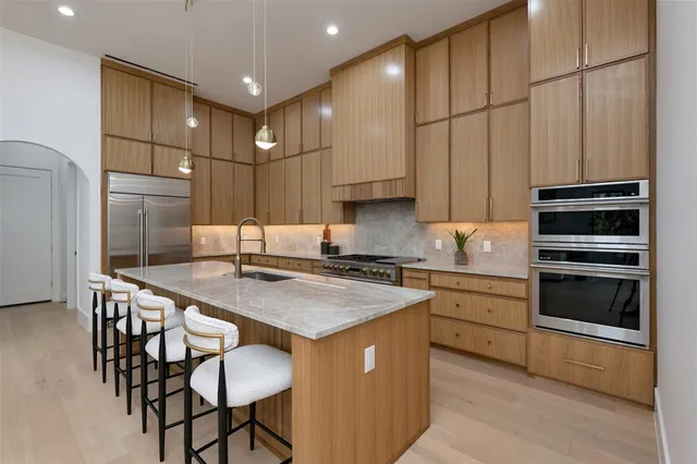 a kitchen with stainless steel appliances granite countertop a table chairs sink and cabinets