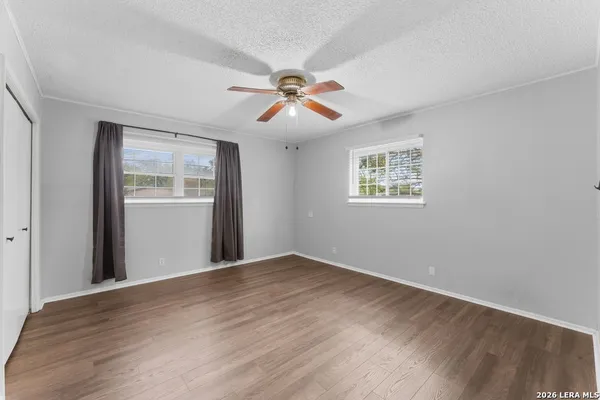 an empty room with wooden floor closet and windows