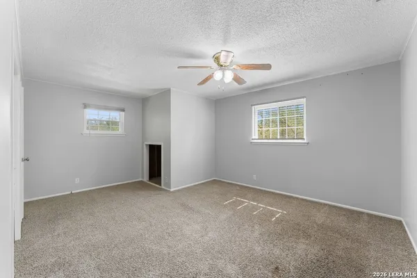 an empty room with windows and ceiling fan