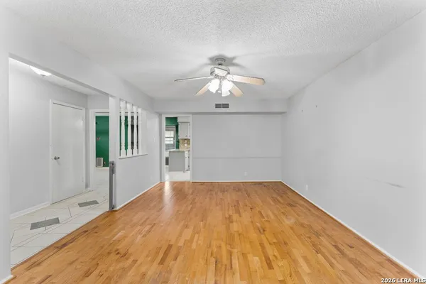 a view of a room with wooden floor and a ceiling fan