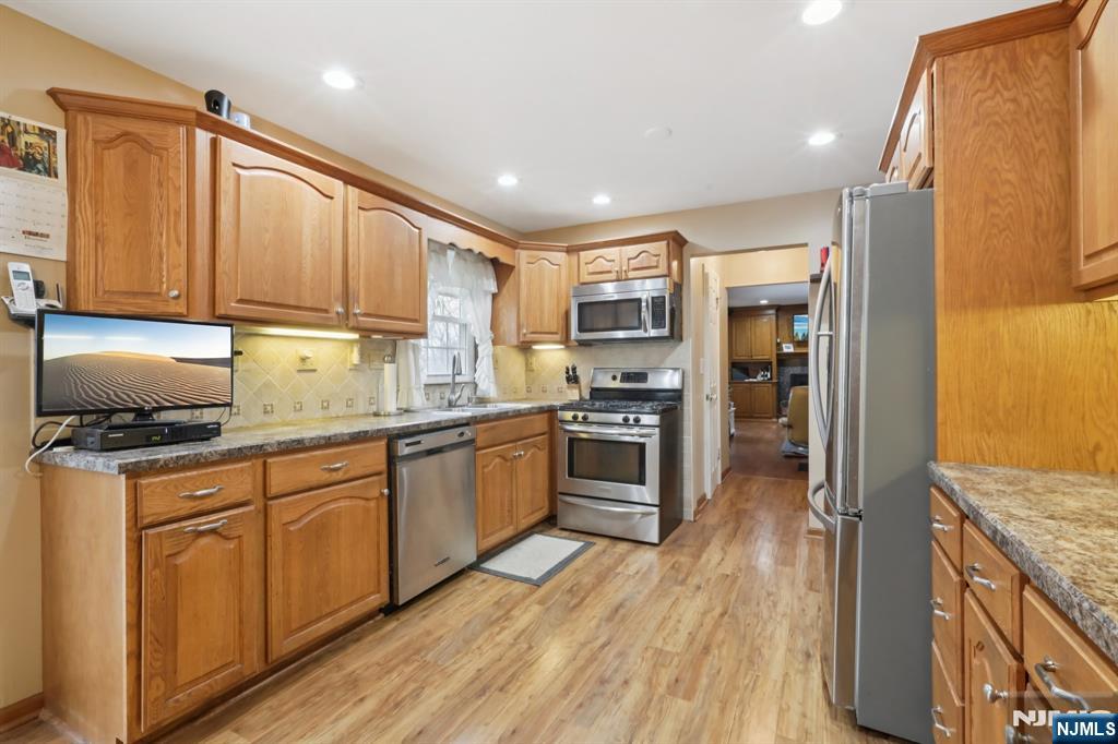 29 Joyce Drive Roxbury Township, NJ 07876 - Photo 11 of 31 a kitchen with granite countertop a stove top oven a sink dishwasher and a refrigerator with wooden floor