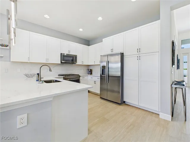 a kitchen with stainless steel appliances a refrigerator sink and white cabinets