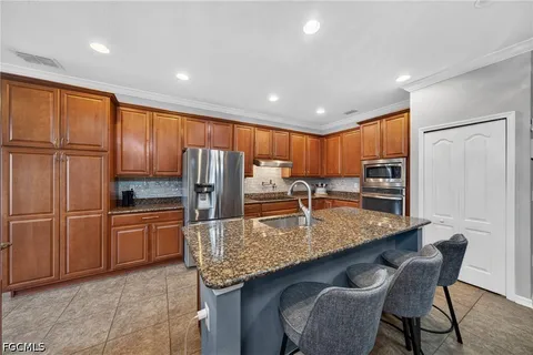 a kitchen with stainless steel appliances granite countertop a refrigerator a sink a stove a dining table and chairs
