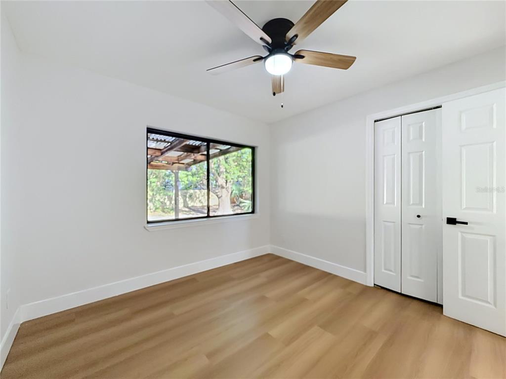 2105 Shaffer Place Orlando, FL 32806 - Photo 39 of 68 an empty room with wooden floor chandelier fan and windows