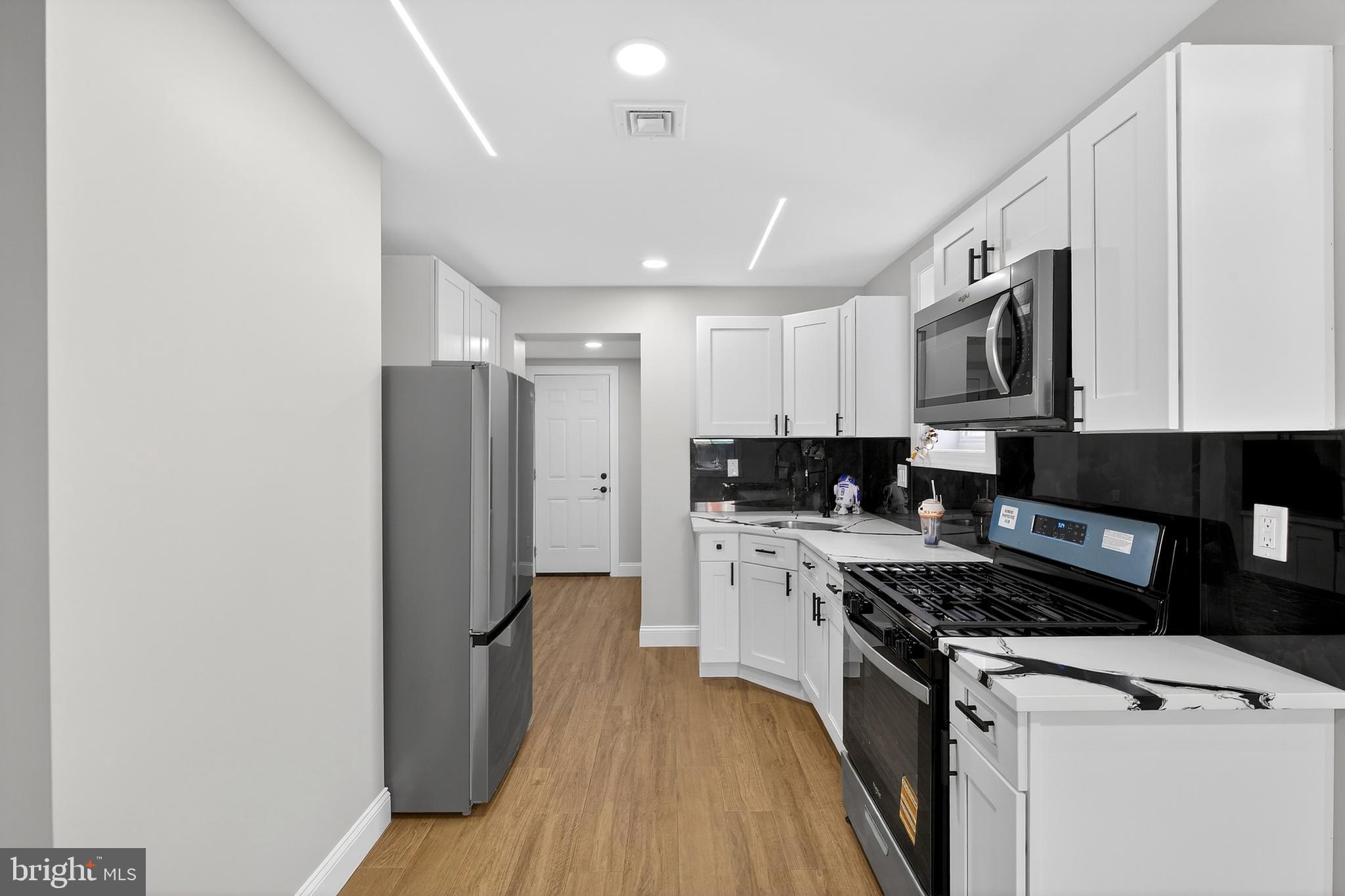 3450 Hurley Street Philadelphia, PA 19134 - Photo 15 of 31 a kitchen with stainless steel appliances granite countertop a stove top oven a refrigerator a sink and dishwasher with wooden floor
