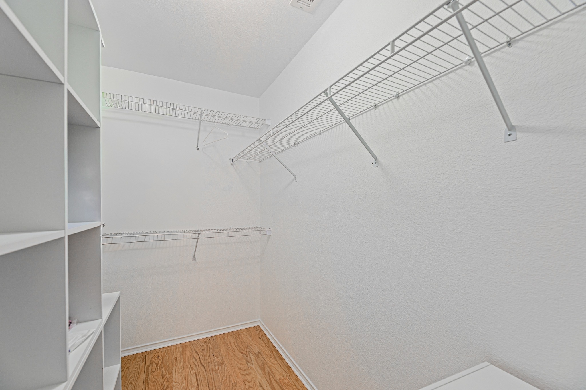 304 River Down Road Georgetown, TX 78628 - Photo 13 of 22 Walk-in closet featuring built-in shelving, wire organization racks, and wood-finish flooring