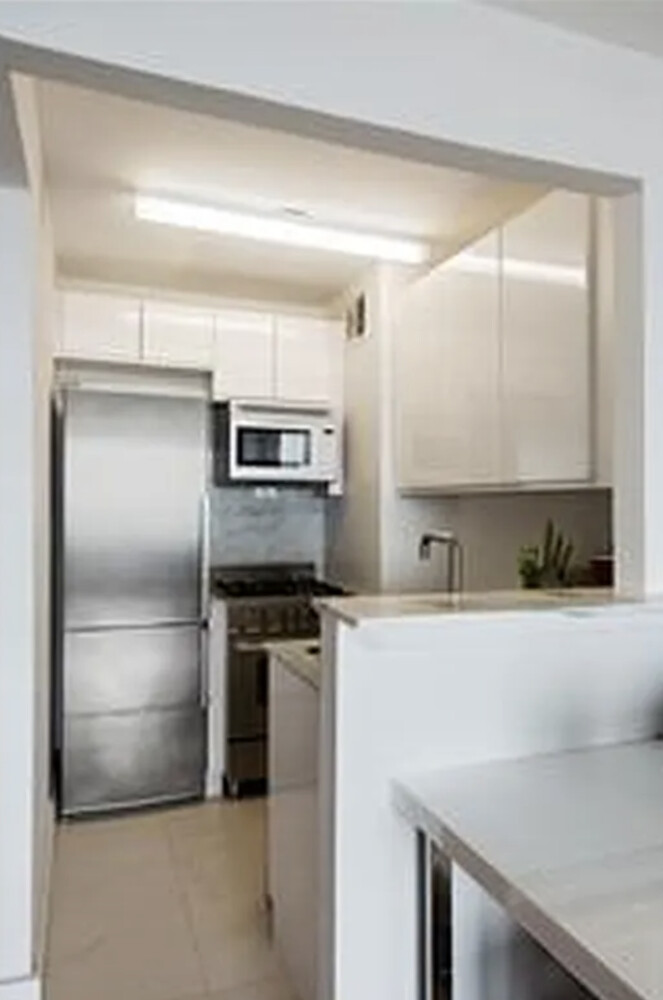 322 West 57th Street, Unit 48F Manhattan, NY 10019 - Photo 4 of 12 a kitchen with stainless steel appliances a sink and a refrigerator